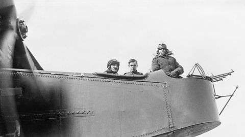 Three airforce men looking out from a plane in World War One