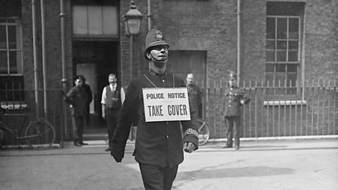 Policemen warning people to take cover during an air raid in World War One