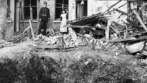 A policeman and two women standing outside a bombed house in Croydon after a Zeppelin attack in October 1915