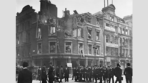 Police and a group of men stand beside a badly damaged building in Aldgate, London in World War One