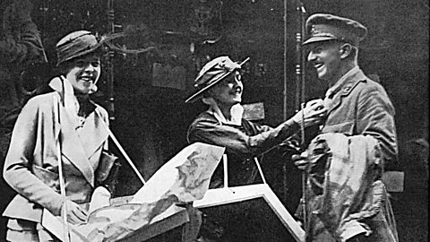 A photograph of two girls selling little flags to a soldier in World War One