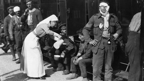 A World War One nurse serving tea to wounded British soldiers beside a railway carriage