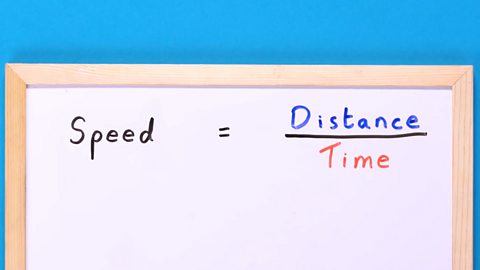 A whiteboard with the formula for speed written on it