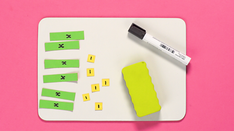 Picture showing a white board, with rubber, tiles with x's on them and tiles of the number 1.