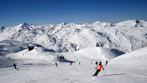 mountains covered in snow with people skiing