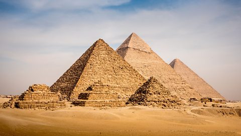 A photo of six pyramids. There are three small pyramids in the foreground and three big pyramids behind them. The tallest pyramid is in the middle at the back.