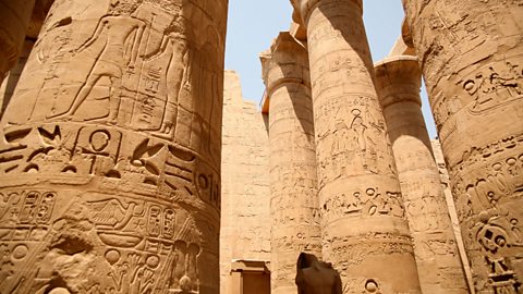 A photo of the huge temple columns at Karnak. The columns have lots of hieroglyphs and pictures of gods carved into them.