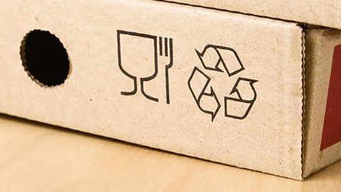 The recycling symbol of three arrows twisting to form a triangle on two pizza boxes.