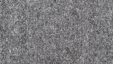 A close-up of a zig-zagged herringbone weave within a dark grey fabric.