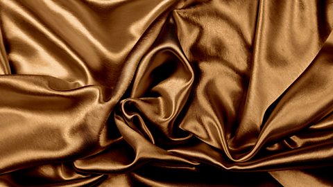 A close-up of a silky satin weave within a golden fabric.