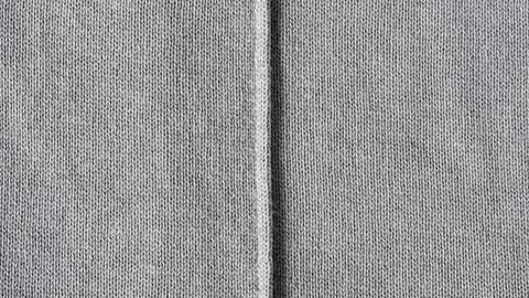 A thin fold in a light grey, tight-knitted fabric is a French seam.