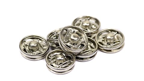 A pile of small, metal press fasteners against a white background.