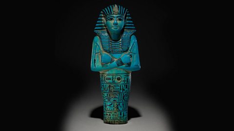 A photo of a blue glazed shabti figure with details painted in black