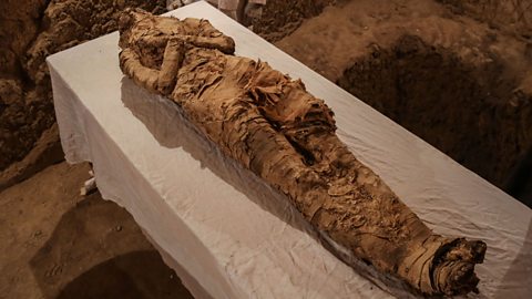 A photo of a scruffy and decayed mummified body found in a tomb in Egypt.