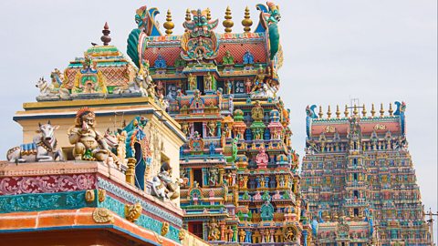 A colourful temple with intricate carvings and statues against a white sky. 