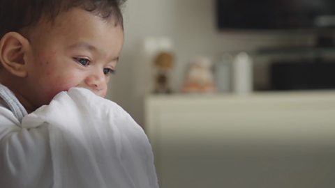 A baby boy biting down on a blanket