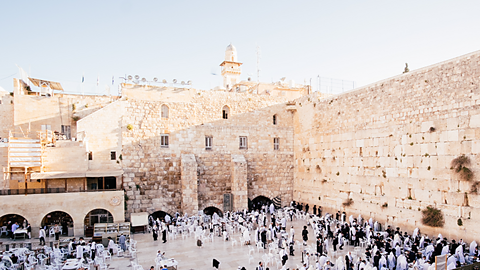 Large crowds of people, occupy the grounds inside the ancient walls of a city. 