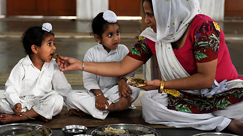 Two young Sikhs are being fed by their mother 