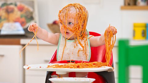 A baby with spaghetti all over themselves.