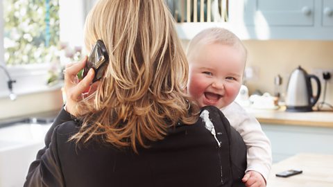 A businesswoman holding a baby who's just been sick on her shoulder.