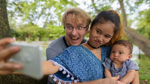 A family taking a selfie, baby looking very unimpressed.