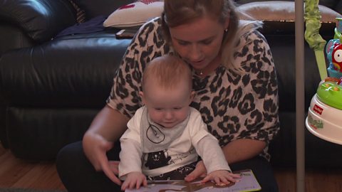 Alison looking at a book with baby Austin.