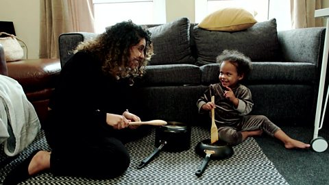 A mum hits pots and pans with her daughter.