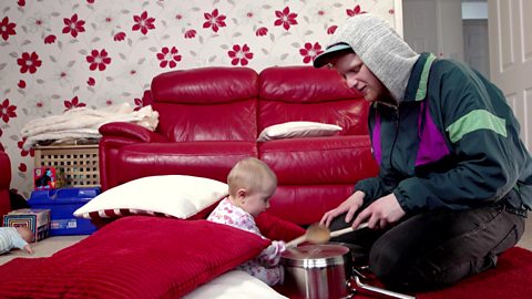 A dad and his daughter playing drums with pots and pans.