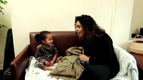 A mum and her little girl playing with a pillowcase full of items.