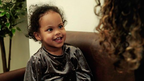 A little girl smiling at her mum.