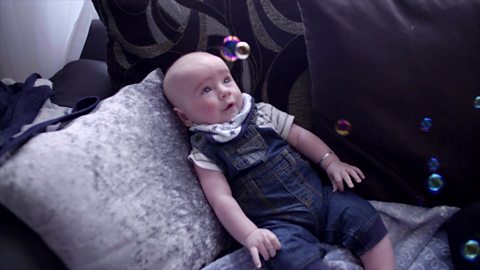 Baby watching floating bubbles in the air.