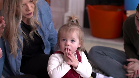 A little girl looking apologetic after knocking down some building blocks.