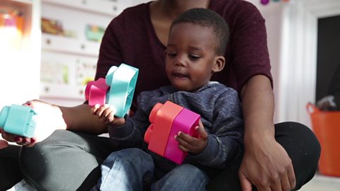 A little boy holding some building blocks.