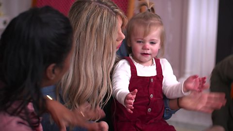 A little girl clapping along to a rhyme.