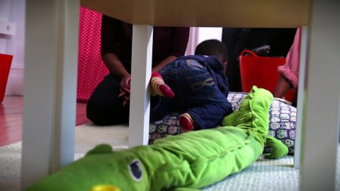 A little boy clambering over some cushions.