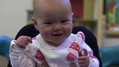 Baby smiling on Mum's knees