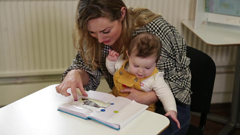 Mum showing a photo book to her baby