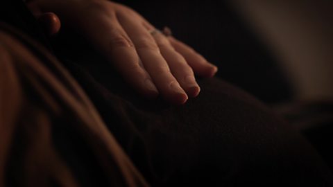 A hand patting a pregnant bump.