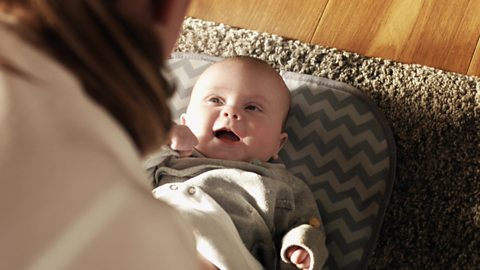 A baby smiling up at his mother.