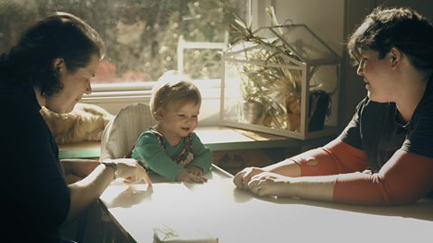 Two mums singing a rhyme with their daughter.