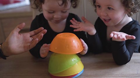 Twin little girls playing with stacking cups.