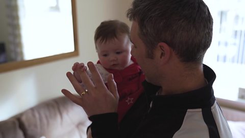 A dad holding and chatting to his baby daughter.