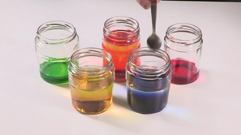 A spoon being tapped on the edge of a jam jar.