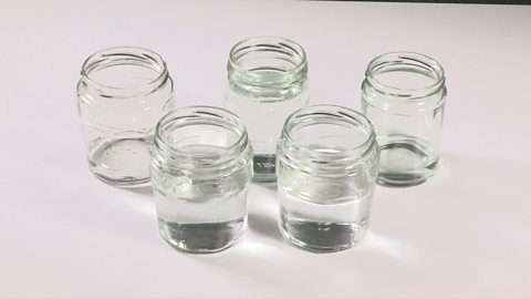 5 jam jars filled with different amounts of water.