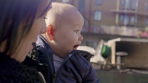 A mum talking to her baby about something he is smiling at.