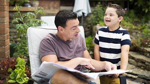 Dad and son in a garden looking at a newspaper