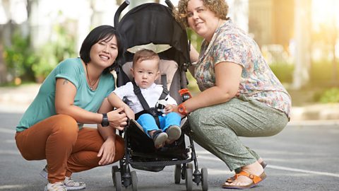 A child in a pushchair with two mums