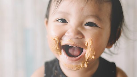 A baby girl with food all around her mouth.