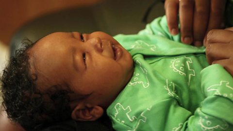 A smiling baby cooing at his mum.