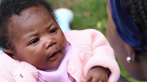 A baby girl staring up at her mum's face.